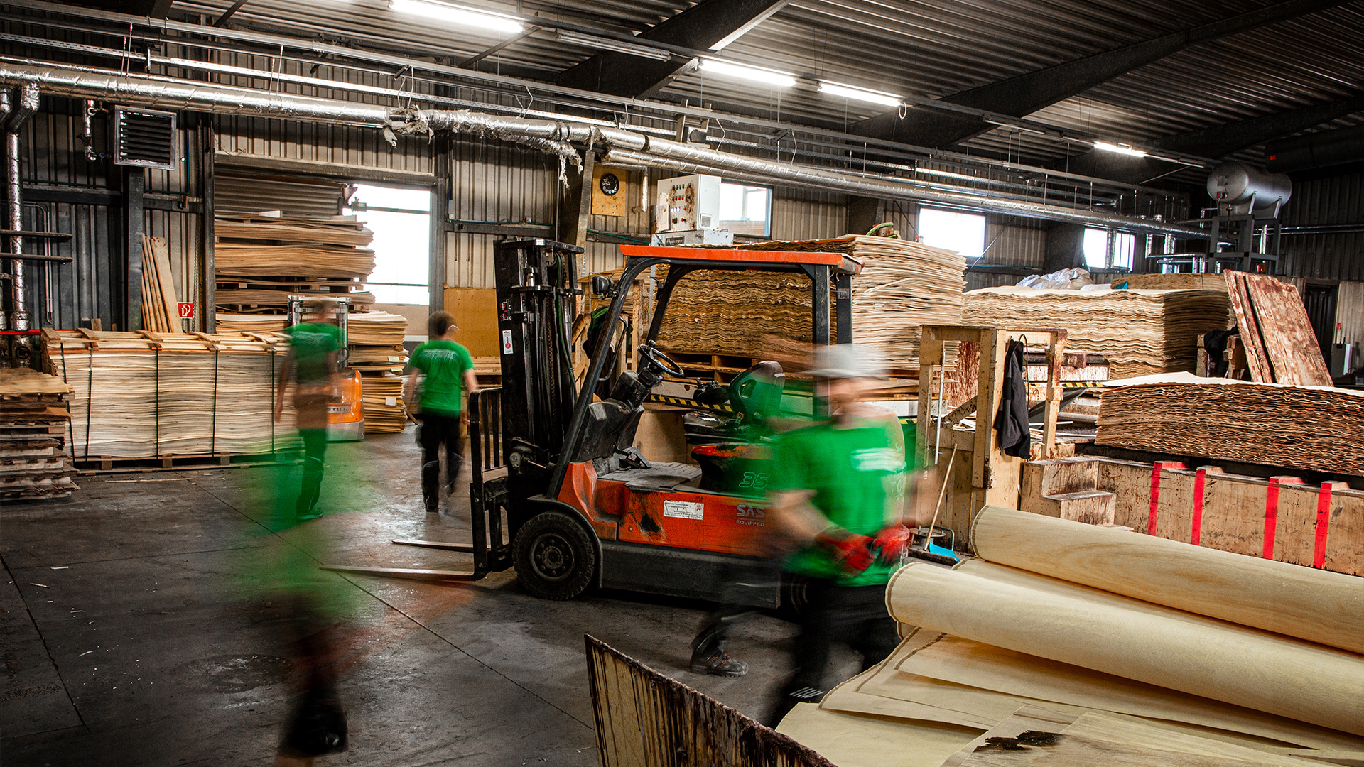 Broszeit Group Holz-Produktionsmitarbeiter in grünem T-Shirt in der Produktionshalle der Neugersdorfer Holzwerke
